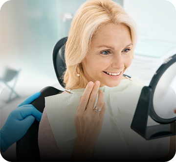 Blonde woman checking smile in handheld mirror